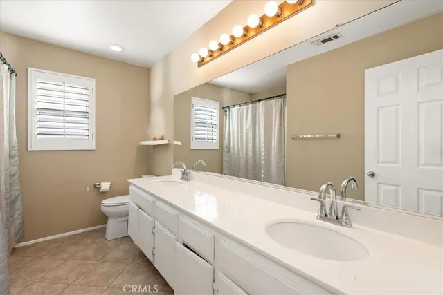 a spacious bathroom with a double vanity sink toilet and a mirror
