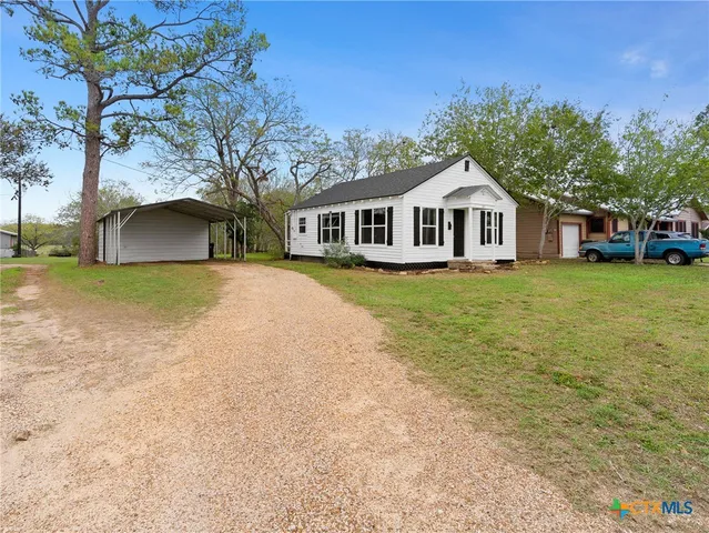 a view of a house with a yard and large trees
