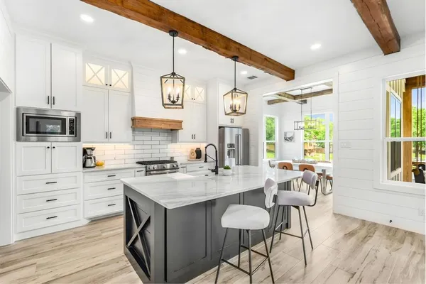 a kitchen with stainless steel appliances kitchen island granite countertop a dining table chairs and granite counter tops