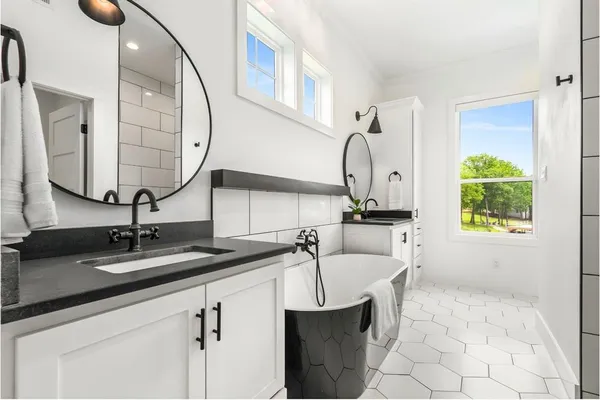 a bedroom with a bed lamp on table and a large window