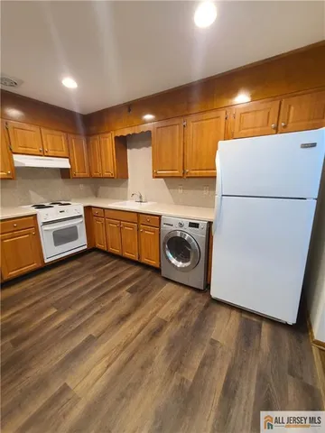 a kitchen with a refrigerator a stove a sink dishwasher and wooden cabinets with wooden floor