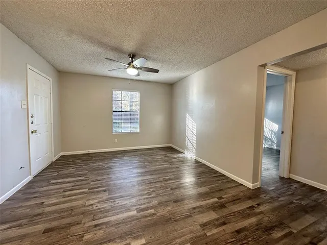 an empty room with wooden floor chandelier and windows