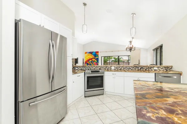 a kitchen with stainless steel appliances granite countertop a refrigerator a stove and a sink