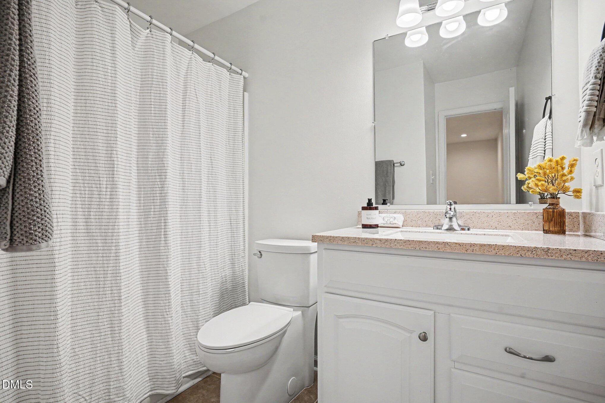 3555 Mill Run Raleigh, NC 27612 - Photo 8 of 25 a bathroom with a granite countertop sink a toilet and a mirror