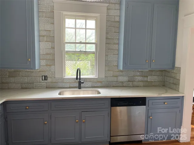 a kitchen with granite countertop white cabinets and a sink