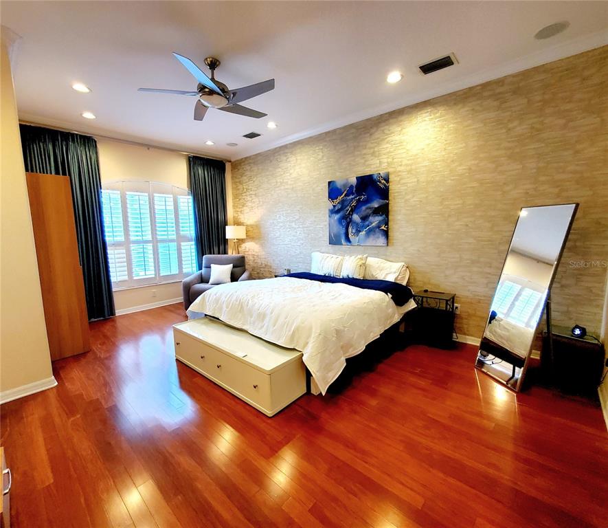 10004 Tree Tops Lake Road Tampa, FL 33626 - Photo 25 of 74 a spacious bedroom with a bed and wooden floor