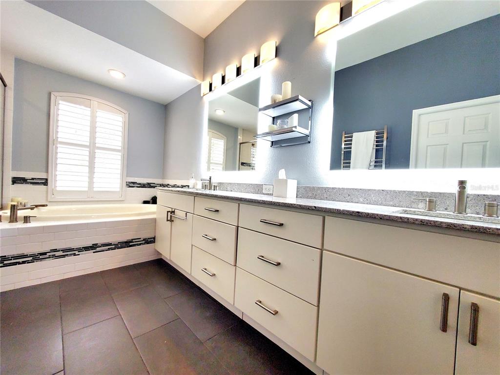 10004 Tree Tops Lake Road Tampa, FL 33626 - Photo 32 of 74 a spacious bathroom with a granite countertop double vanity sink a mirror and a bathtub
