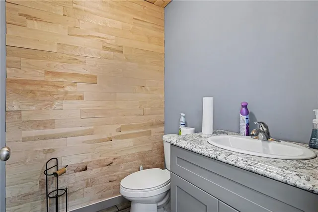 a bathroom with a granite countertop toilet a sink and mirror