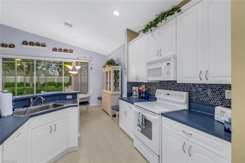 9054 Springview Loop Estero, FL 33928 - Photo 9 of 24 a kitchen that has a lot of white cabinets and wooden floor