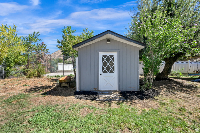 1003 East Maple Street Mapleton, UT 84664 - Photo 29 of 32 Storage shed with gray siding, a black shingled roof, and a white door with diamond-pane glass