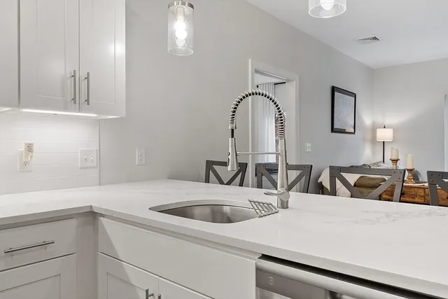 a close view of a sink and dishwasher with kitchen island