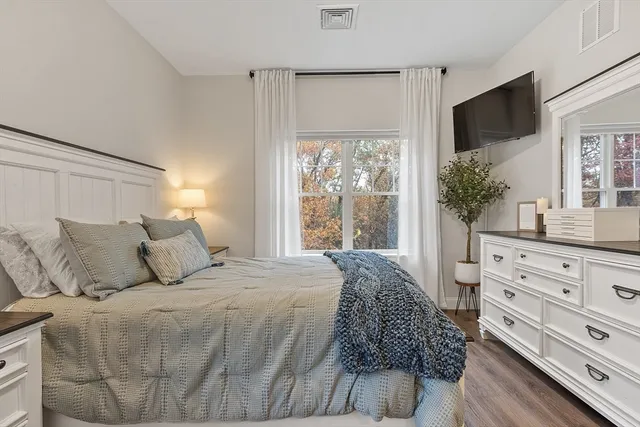 a bedroom with a large bed and a flat tv screen on dresser