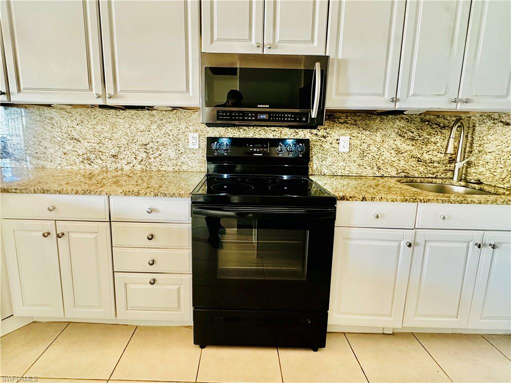 826 Wiggins Pass Road, Unit 307 Naples, FL 34110 - Photo 6 of 17 a kitchen with granite countertop white cabinets and stainless steel appliances