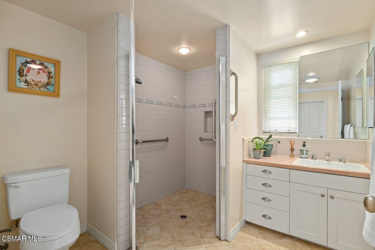 11616 Clarkson Road Los Angeles, CA 90064 - Photo 19 of 34 a bathroom with a toilet a sink a glass door a shower a mirror and vanity