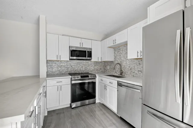 a kitchen with white cabinets and stainless steel appliances