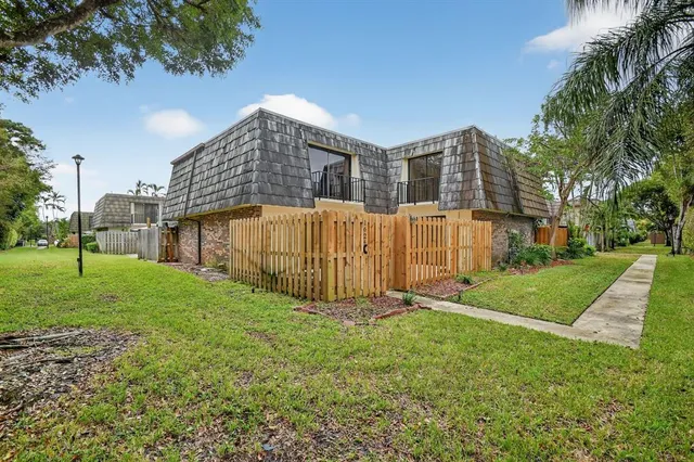 a view of an house with backyard and a tree