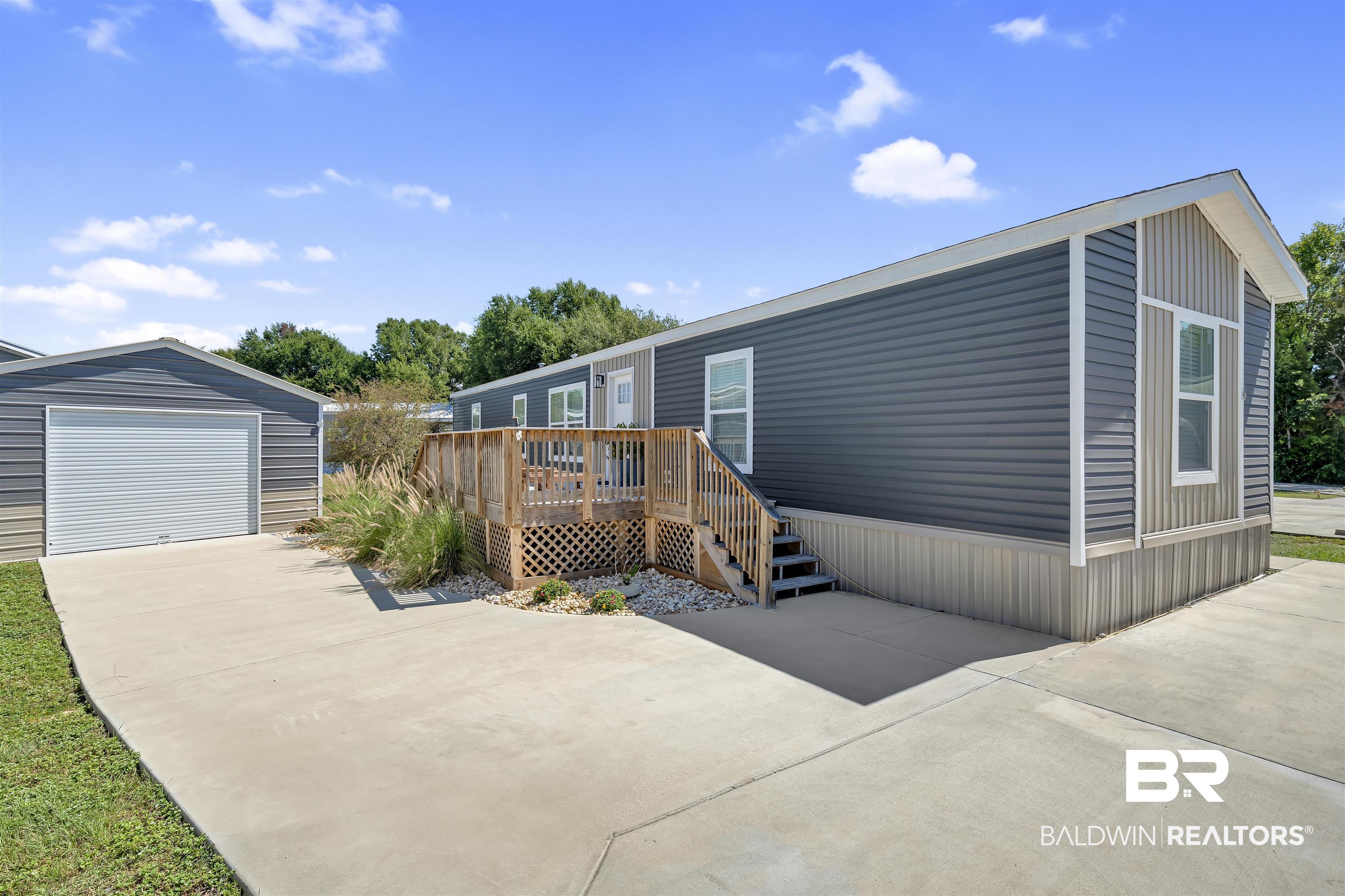 16707 Fort Morgan Road Gulf Shores, AL 36542 - Photo 1 of 22 Manufactured / mobile home with an outdoor structure, a wooden deck, driveway, and a garage