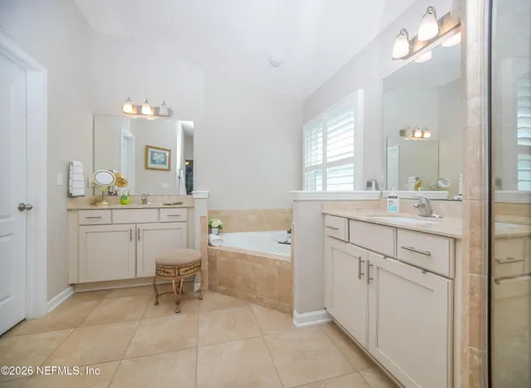 a spacious bathroom with a sink a chair a mirror and a bathtub