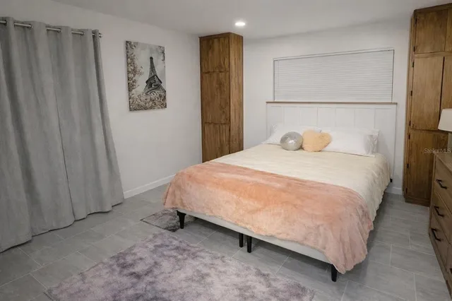 a view of a swimming pool with lawn chairs under an umbrella and palm trees