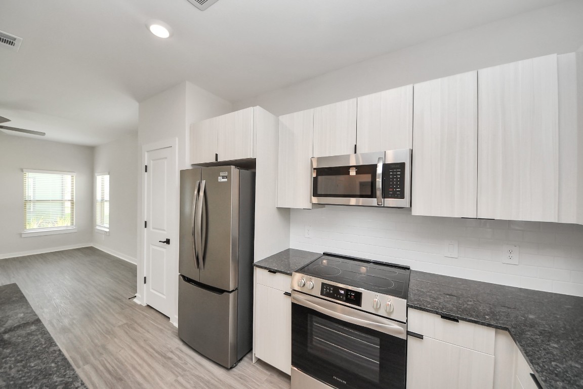 7711 Longmire Road, Unit 158 Conroe, TX 77304 - Photo 41 of 48 Boasting luxury finishes-stylish Island kitchen,granite counters,subway tile backsplash,ample custom cabinet space,stainless appliances,refrigerator,full size washer&dryer included,wood-like flooring throughout,open concept floor plan.