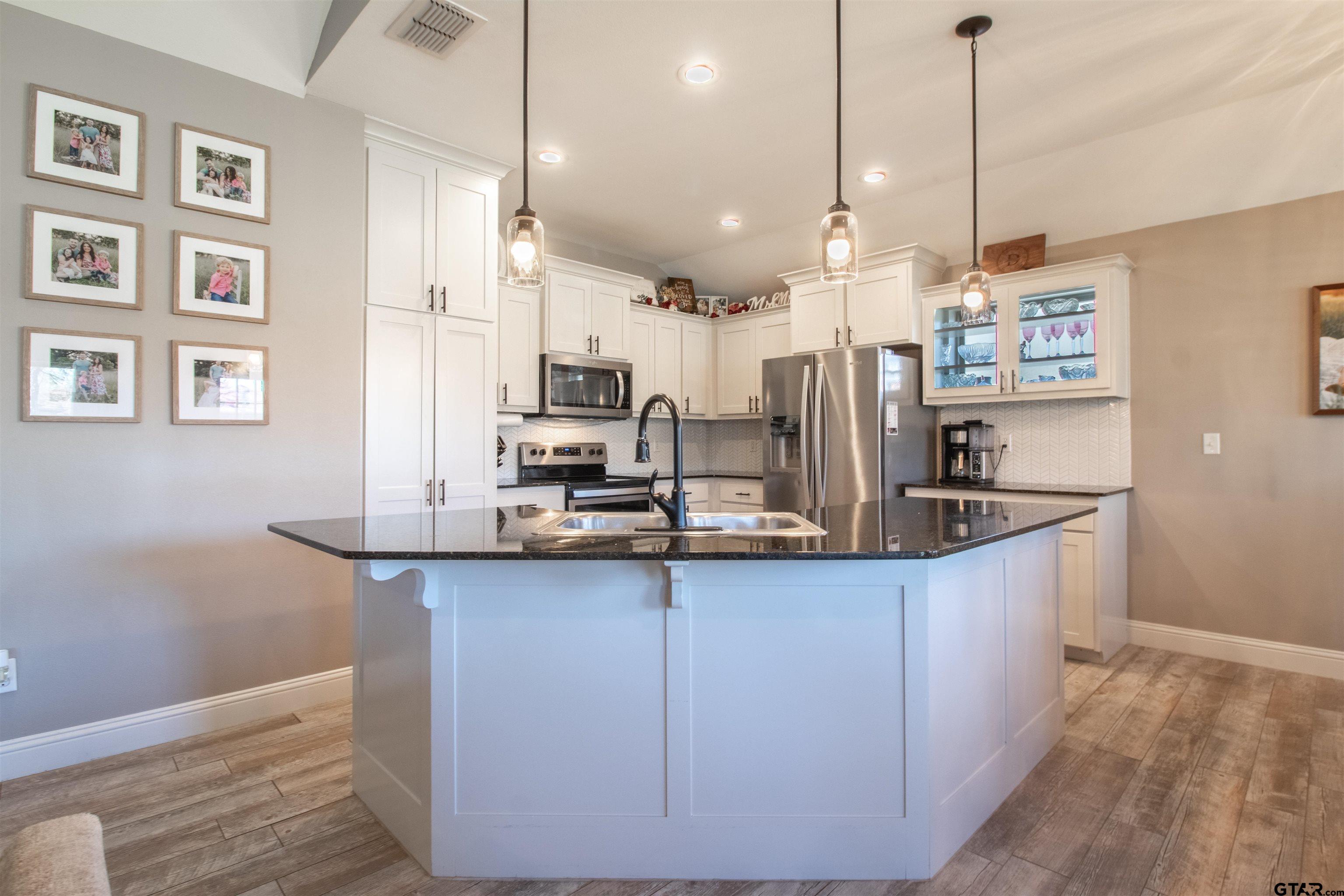 15326 Spring Oaks Drive Lindale, TX 75771 - Photo 9 of 29 a kitchen with stainless steel appliances granite countertop a sink a refrigerator and a wooden floor