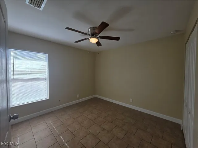 an empty room with windows and fan
