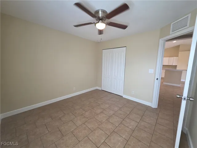 an empty room with closet and a ceiling fan