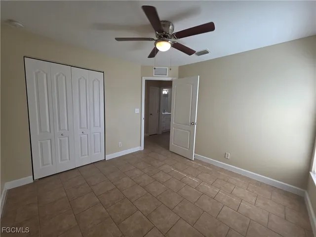 an empty room with closet and a ceiling fan