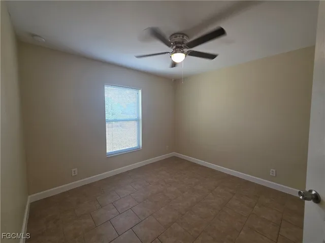 an empty room with a window and a fan