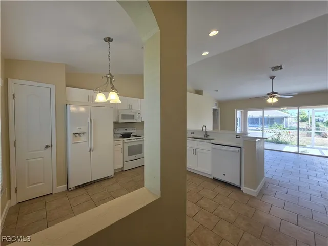 a open kitchen with refrigerator and white cabinets
