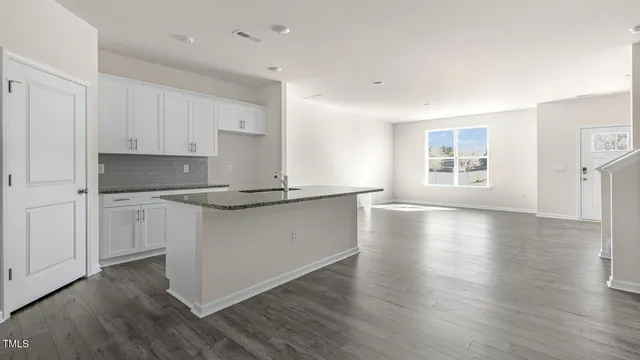 a kitchen with granite countertop white cabinets and wooden floor