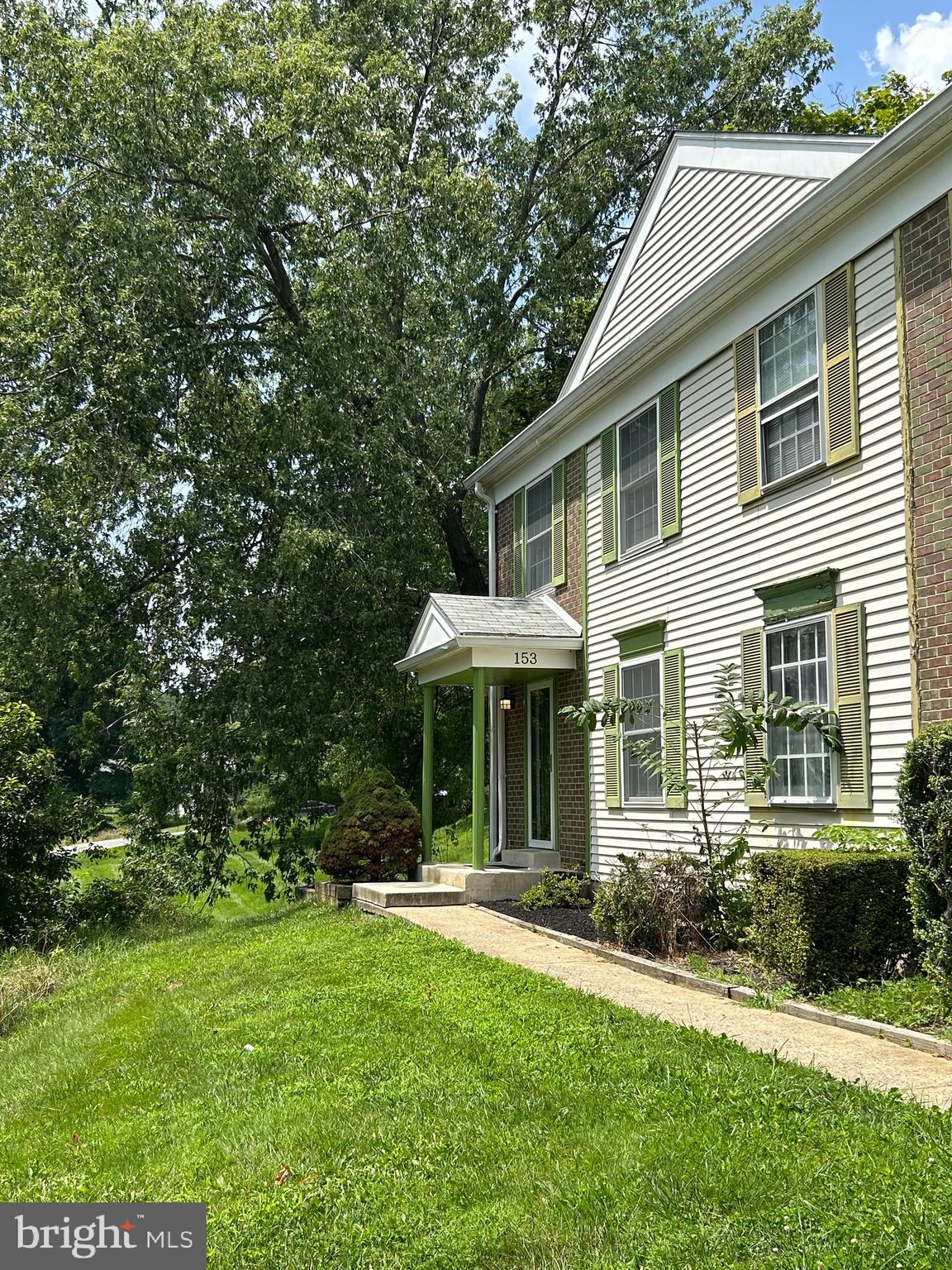 a view of a white house with a big yard and large trees