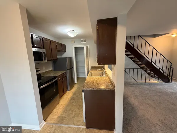 a kitchen with granite countertop a refrigerator a stove and a sink