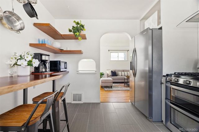 a kitchen with stainless steel appliances kitchen island granite countertop a table chairs in it and wooden floors