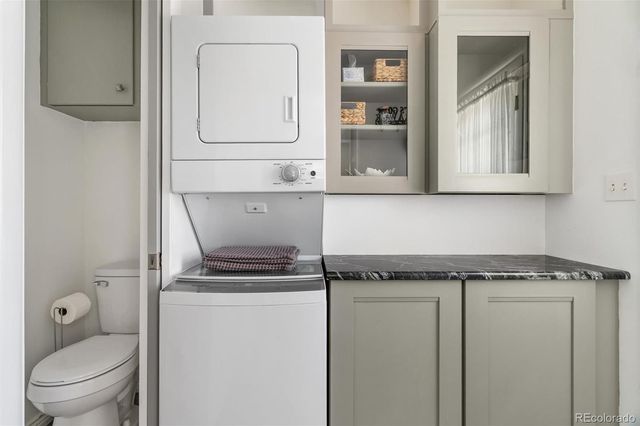 a utility room with granite countertop cabinets and washer