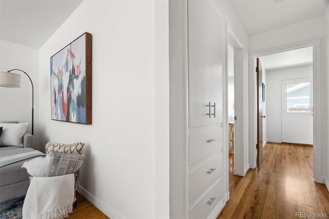a hallway with white doors wooden floor and front door