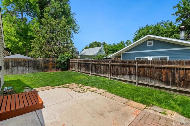 a view of a wooden deck with a big yard and large trees