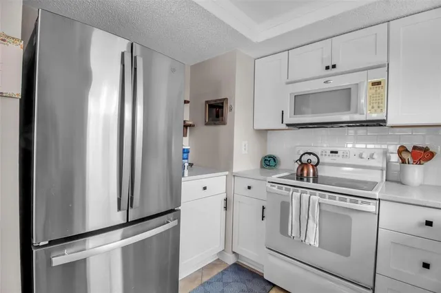a kitchen with stainless steel appliances white cabinets and a refrigerator