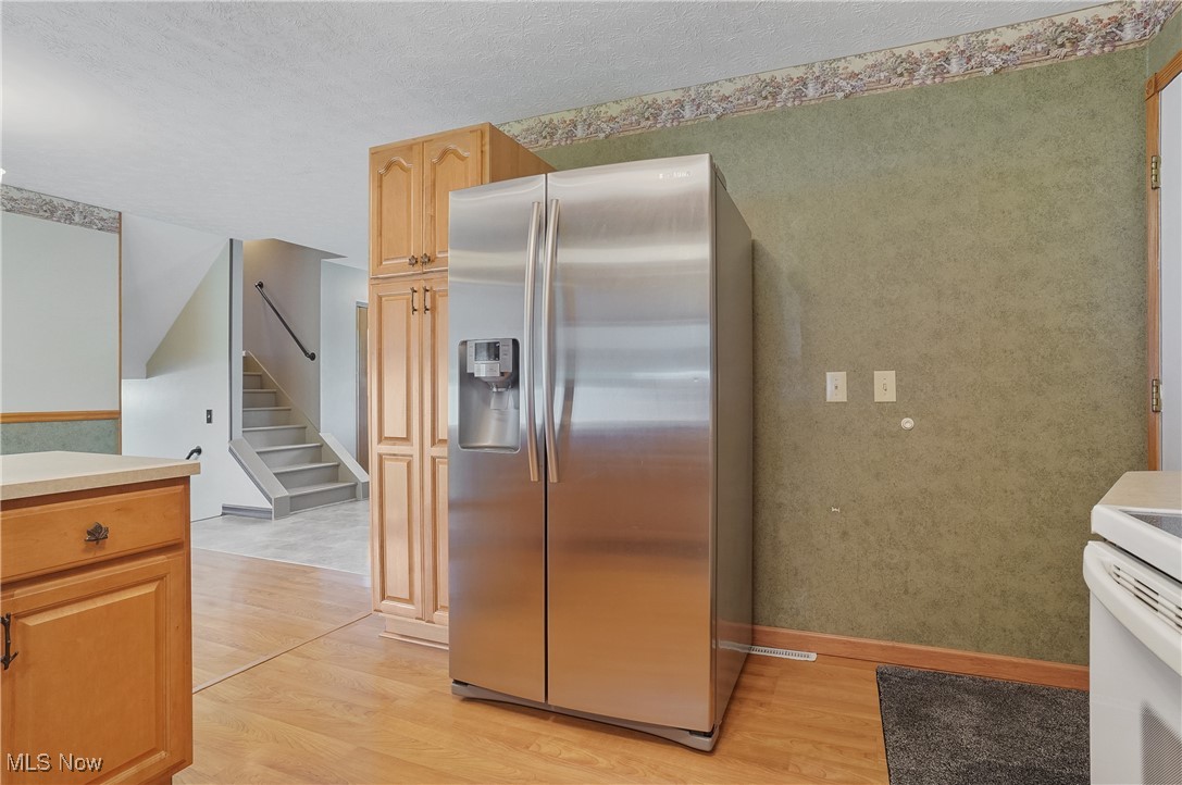 3262 Wright Road Northwest Uniontown, OH 44685 - Photo 17 of 37 Kitchen with stainless steel fridge, light wood-type flooring, light countertops, and a textured ceiling