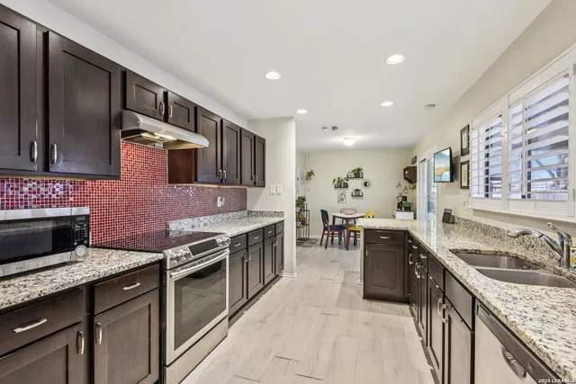 a kitchen with stainless steel appliances granite countertop sink stove top oven and cabinets