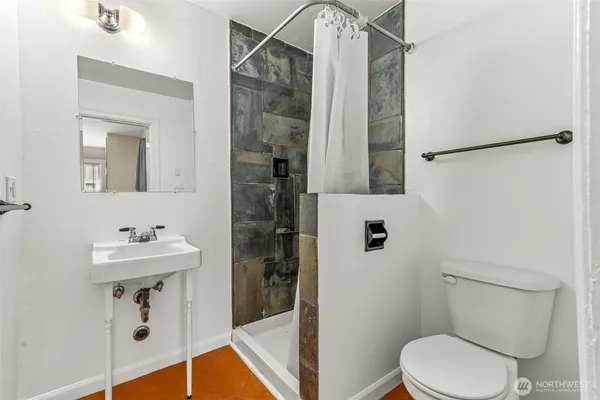 a bathroom with a sink a toilet a mirror and shower