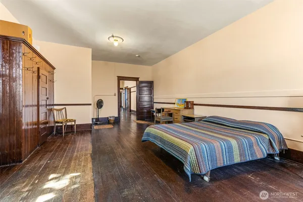 a spacious bedroom with a bed and wooden floor