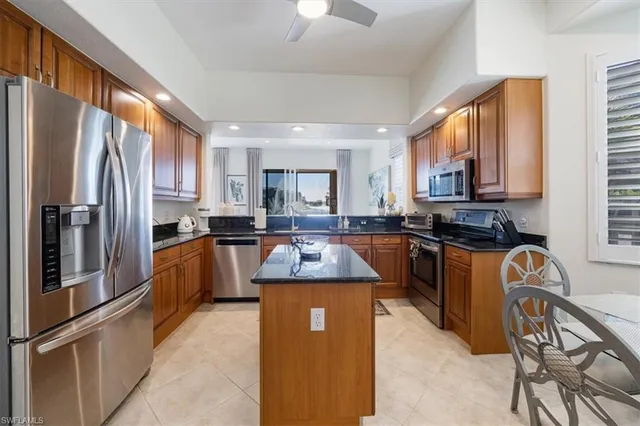 a kitchen with granite countertop stainless steel appliances a refrigerator a stove top oven a sink a dining table and chairs