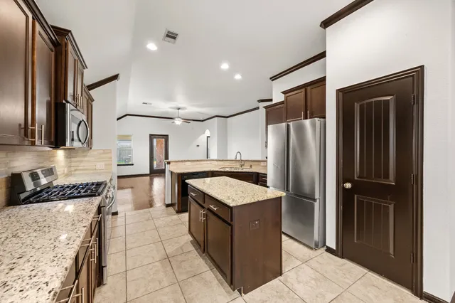 a kitchen with stainless steel appliances granite countertop a refrigerator and a stove