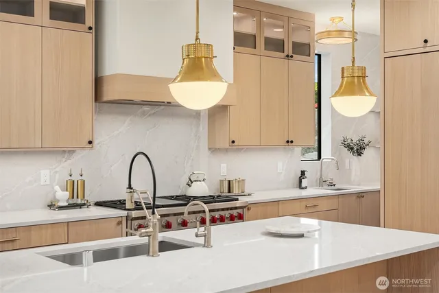 a large kitchen with kitchen island a large window wooden floor and stainless steel appliances