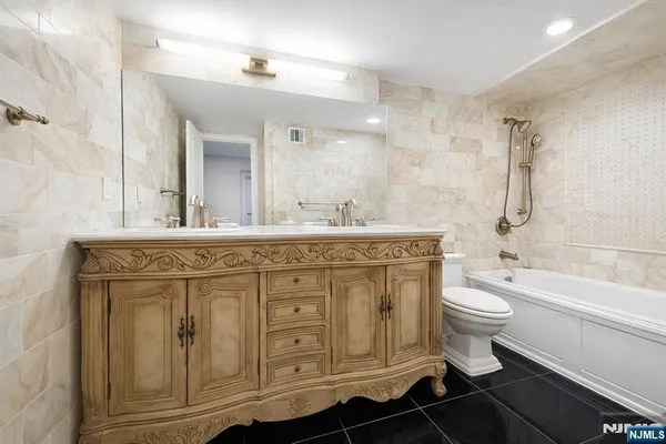 a bathroom with a double vanity sink a toilet a mirror and bathtub
