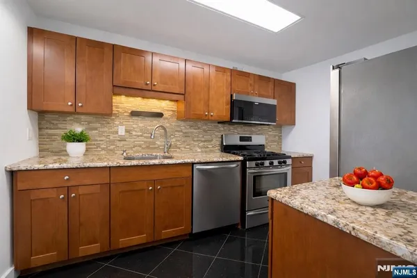 a kitchen with granite countertop cabinets stainless steel appliances and a sink