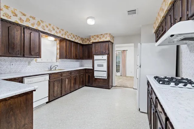 a kitchen with stainless steel appliances granite countertop wooden cabinets a stove top oven a sink and dishwasher