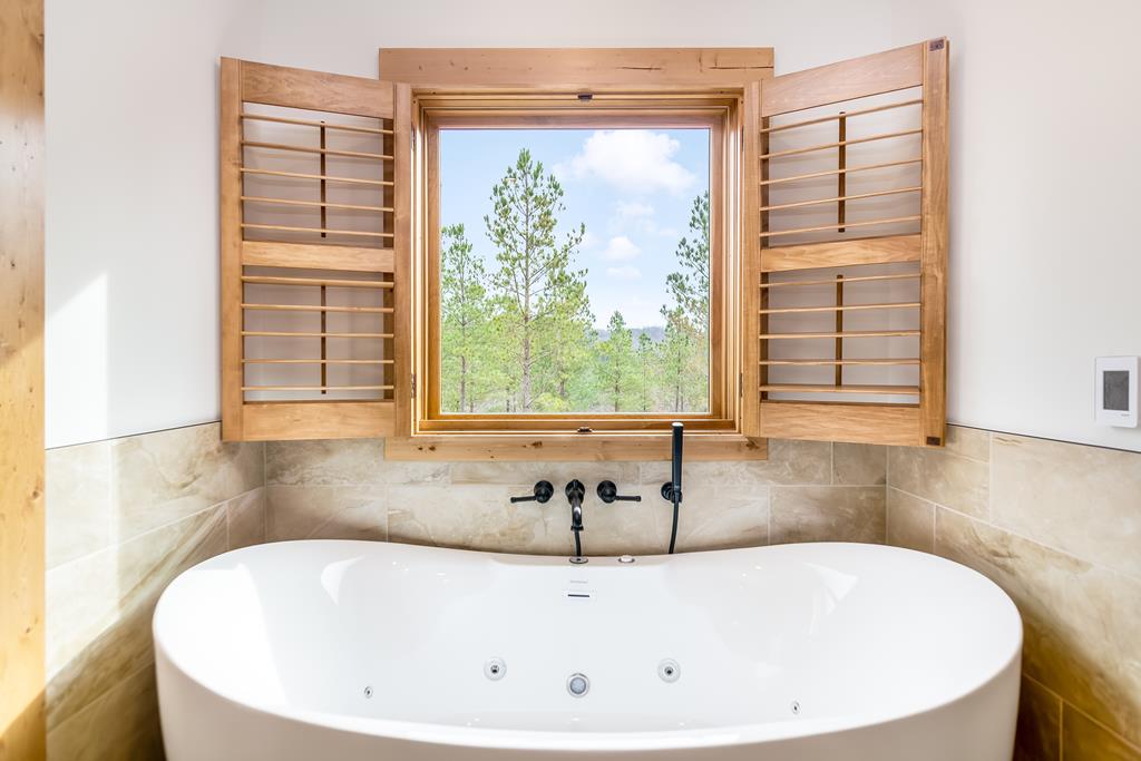 2468 Twisted Oak Road Talking Rock, GA 30175 - Photo 22 of 67 a white bath tub sitting in a bathroom next to a window