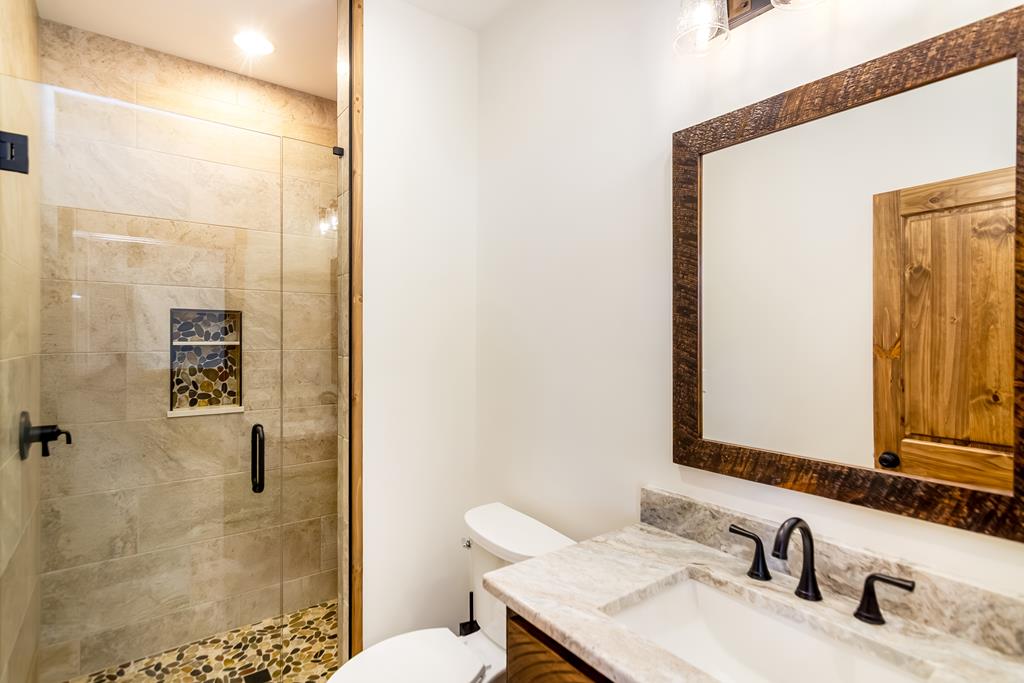 2468 Twisted Oak Road Talking Rock, GA 30175 - Photo 24 of 67 a bathroom with a granite countertop sink toilet and shower